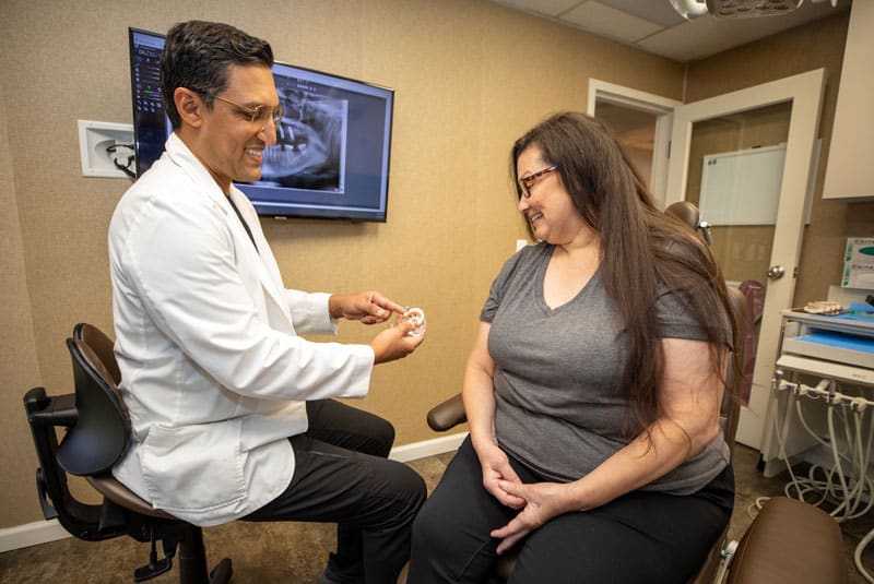 tina looking at bhullar as he points to implant model