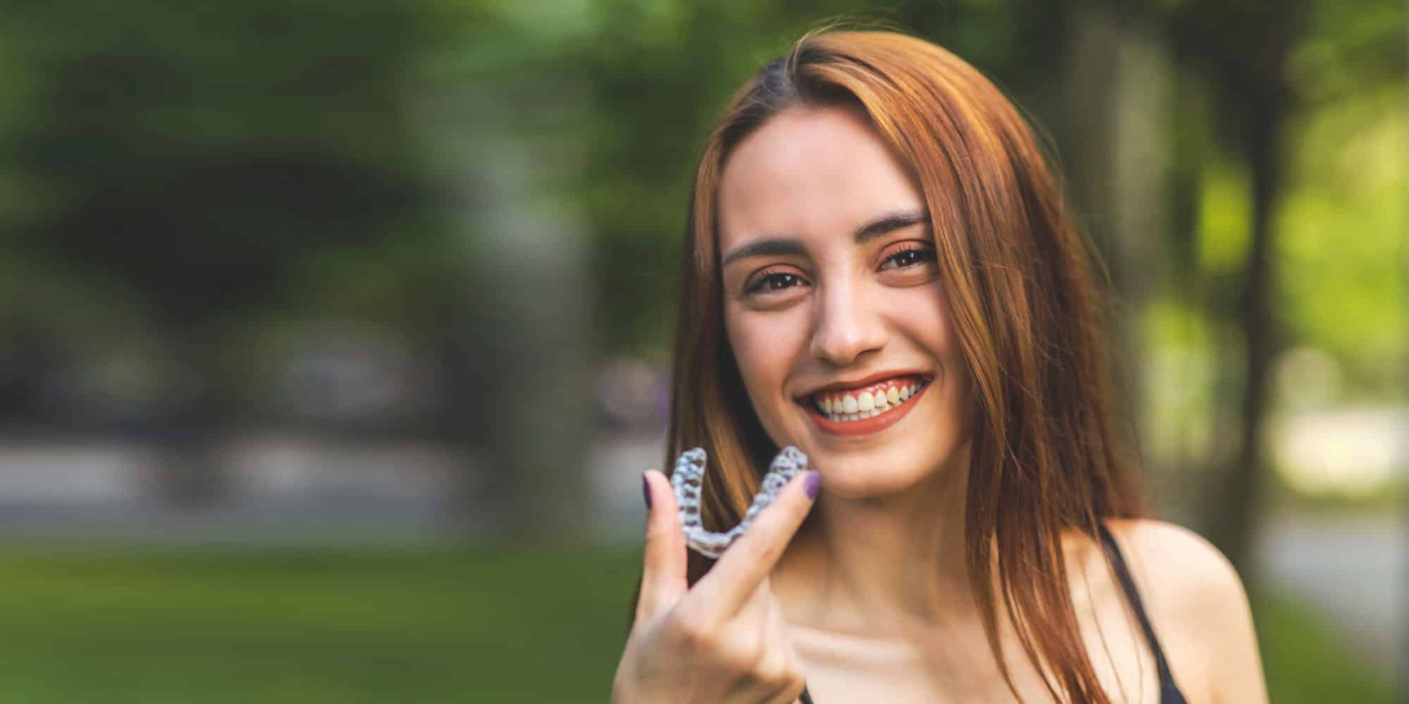 invisalign patient with clear aligner in hand